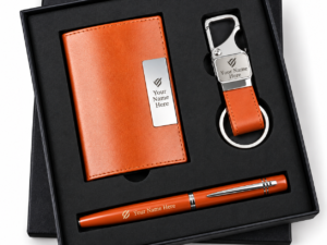 Orange corporate gift set with notebook, pen, and keychain in a black presentation box